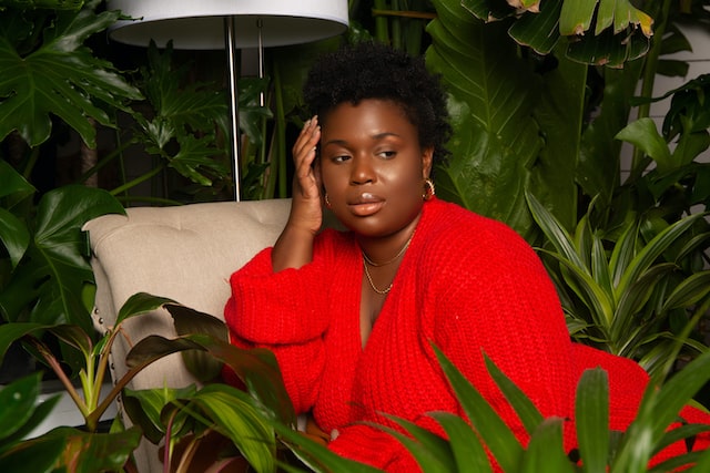 woman in red knit sweater sitting on white couch