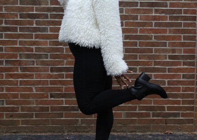 woman raising her left foot near brown brick wall