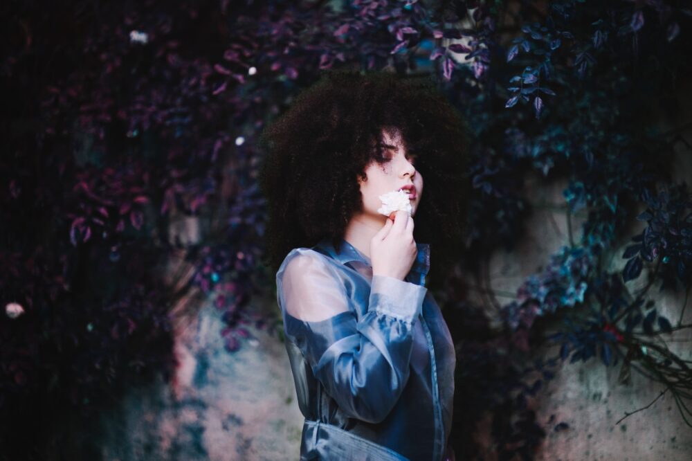 woman standing beside flower wall